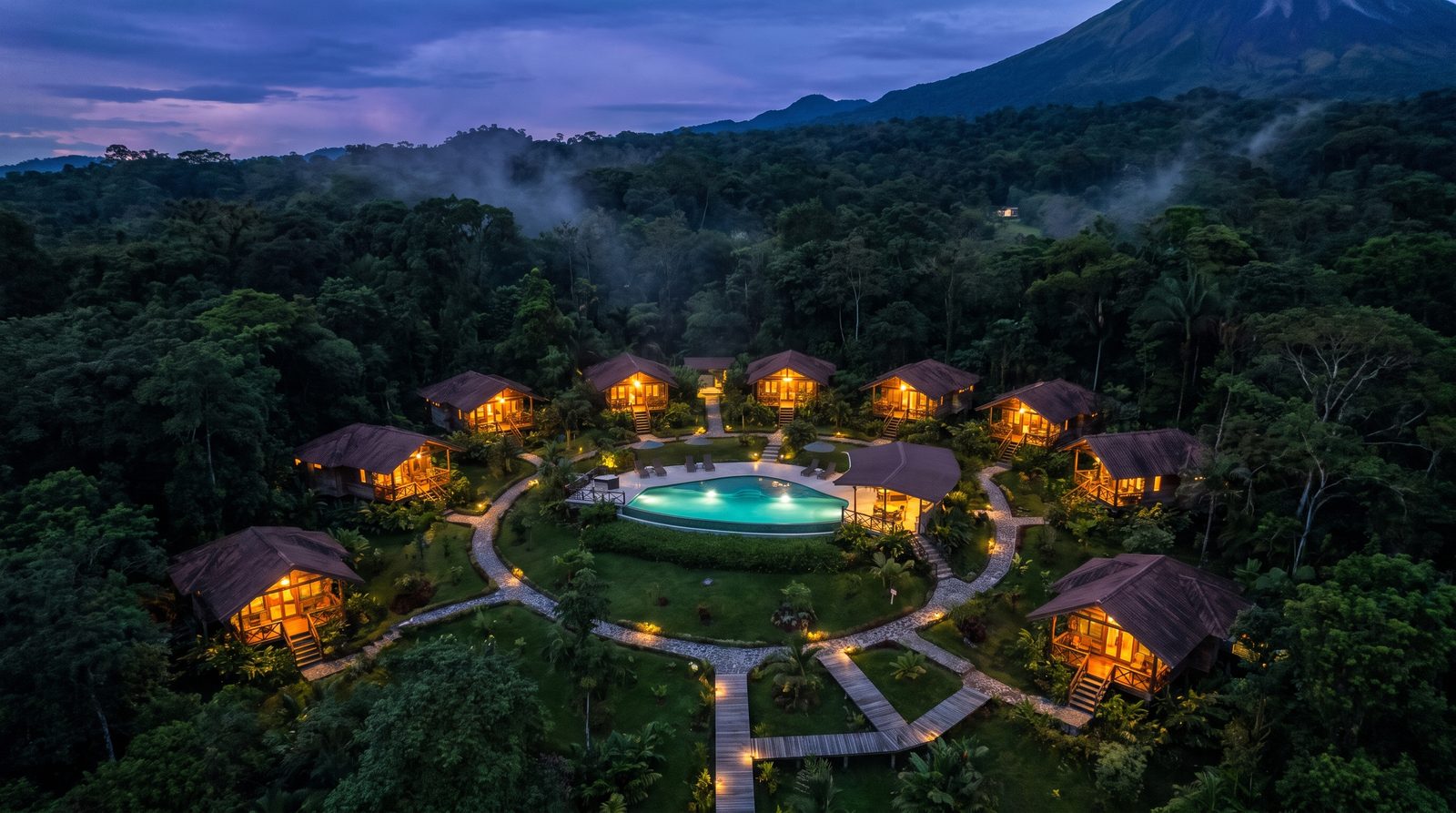 Vista aérea al atardecer de diez villas iluminadas en el bosque tropical